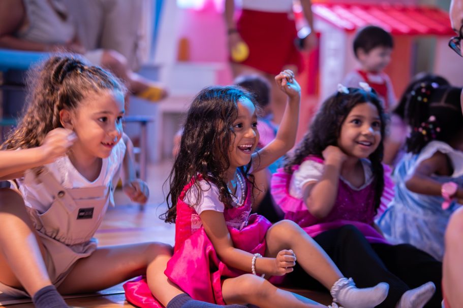 Niñas sonriendo y jugando en un ambiente alegre, vestidas con ropa colorida.