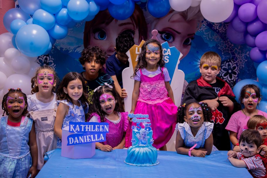 Niños en una fiesta de cumpleaños, disfrazados y sonriendo, con decoración de personajes de Frozen.