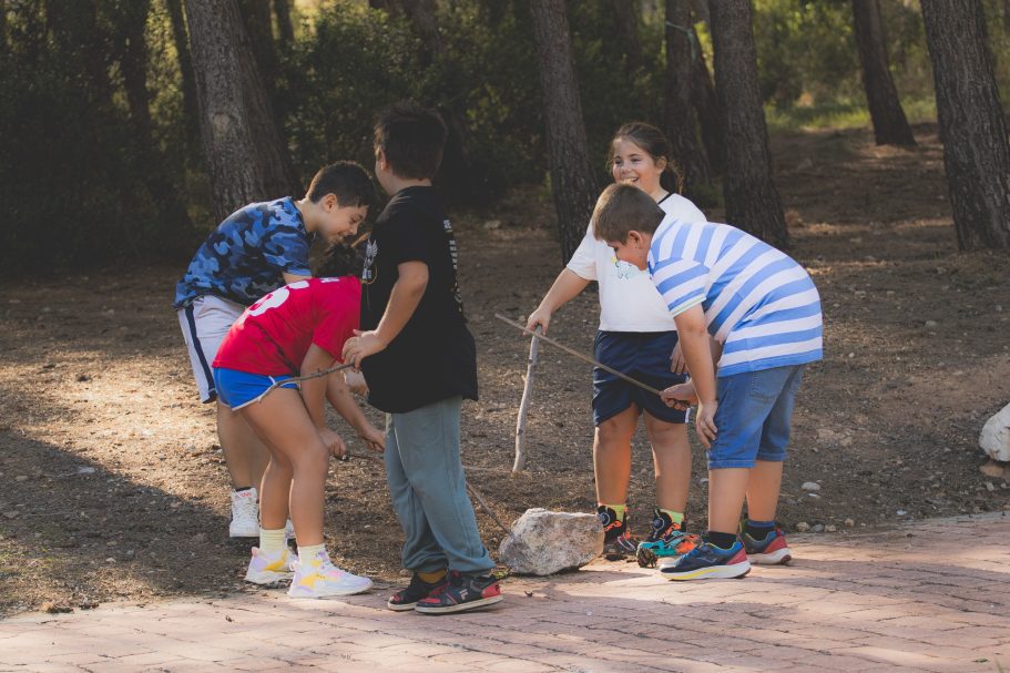 Niños jugando en un parque, observando algo en el suelo.