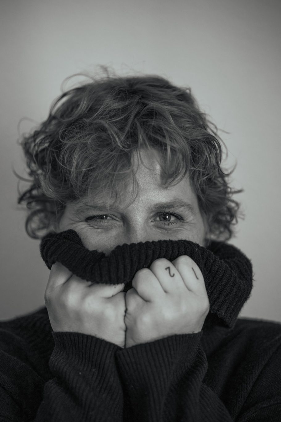 Persona con suéter cubriendo parte de su rostro, expresión de sorpresa o timidez.