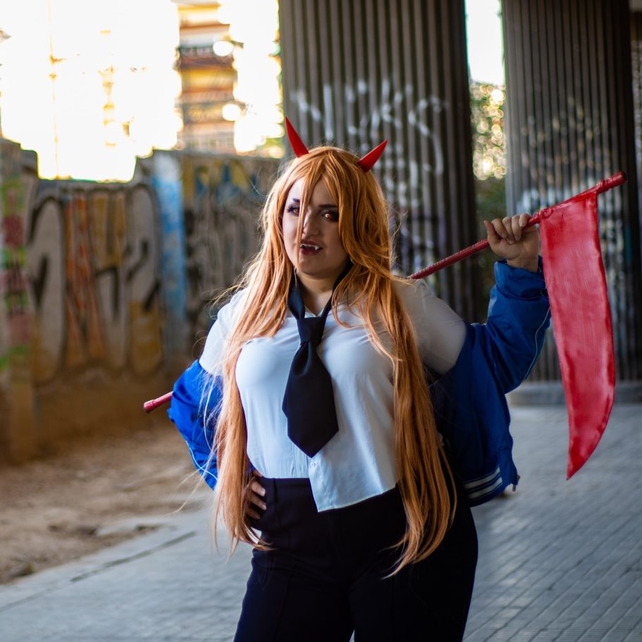 Joven con cabello largo y castaño, vestida de cosplay con una bandera roja.