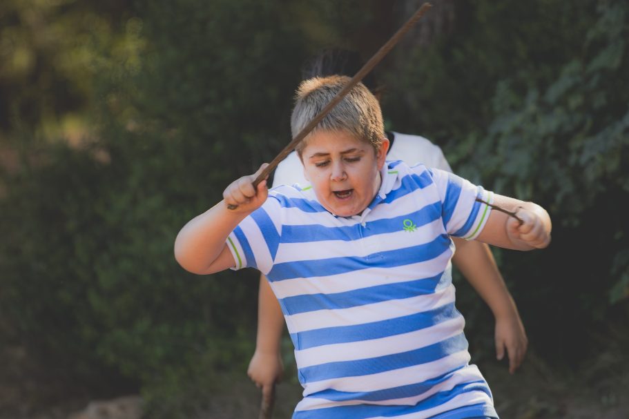 Niño con camiseta de rayas azules y blancas, lanzando un objeto al aire.