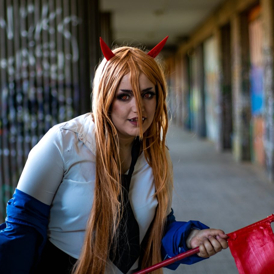 Mujer con cabello largo y cuernos rojos, sosteniendo una pala en un lugar grafiteado.