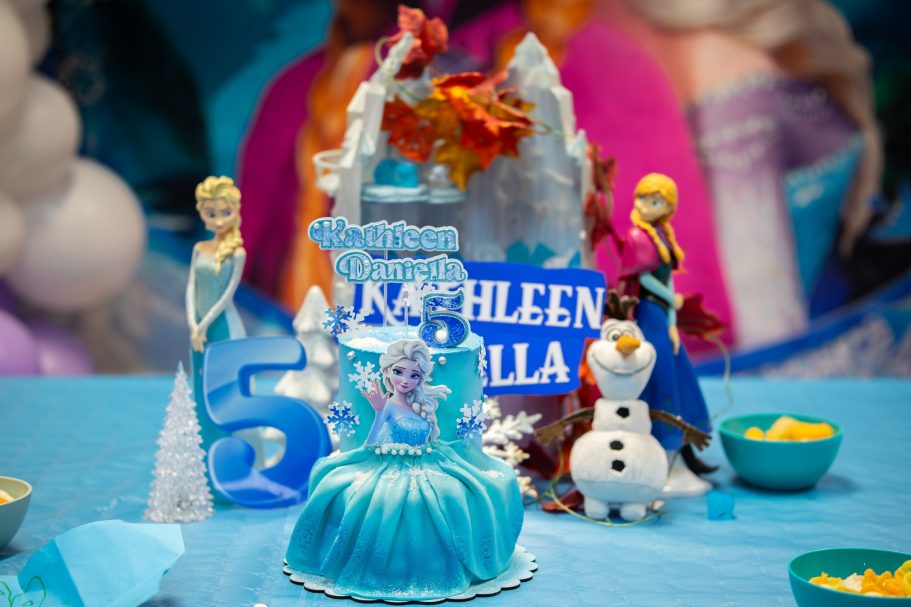 Decoración de cumpleaños temática de Frozen con una tarta y figuras de Elsa y Olaf.