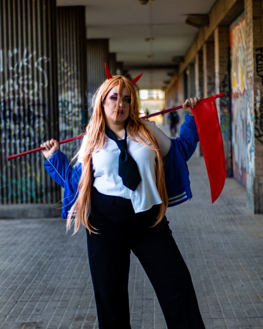 Mujer con cabello largo y rubio, vestida con ropa casual y sosteniendo un hacha roja.