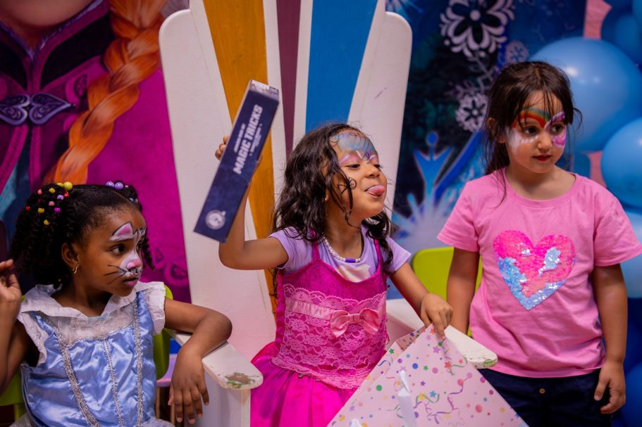 Niñas disfrazadas y pintadas con colores brillantes, celebrando en cumpleaños.