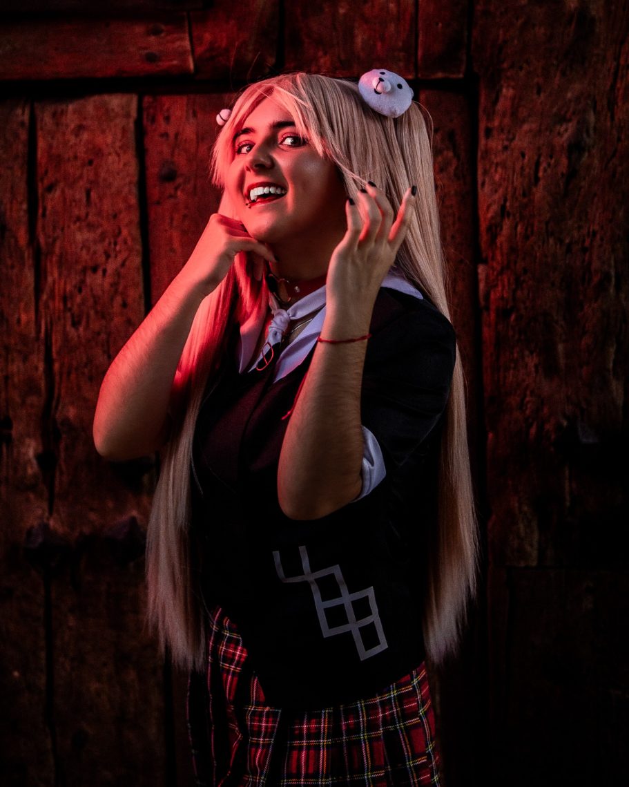 Joven con cabello largo y rubio, vestida con uniforme escolar y fondo con luz roja.