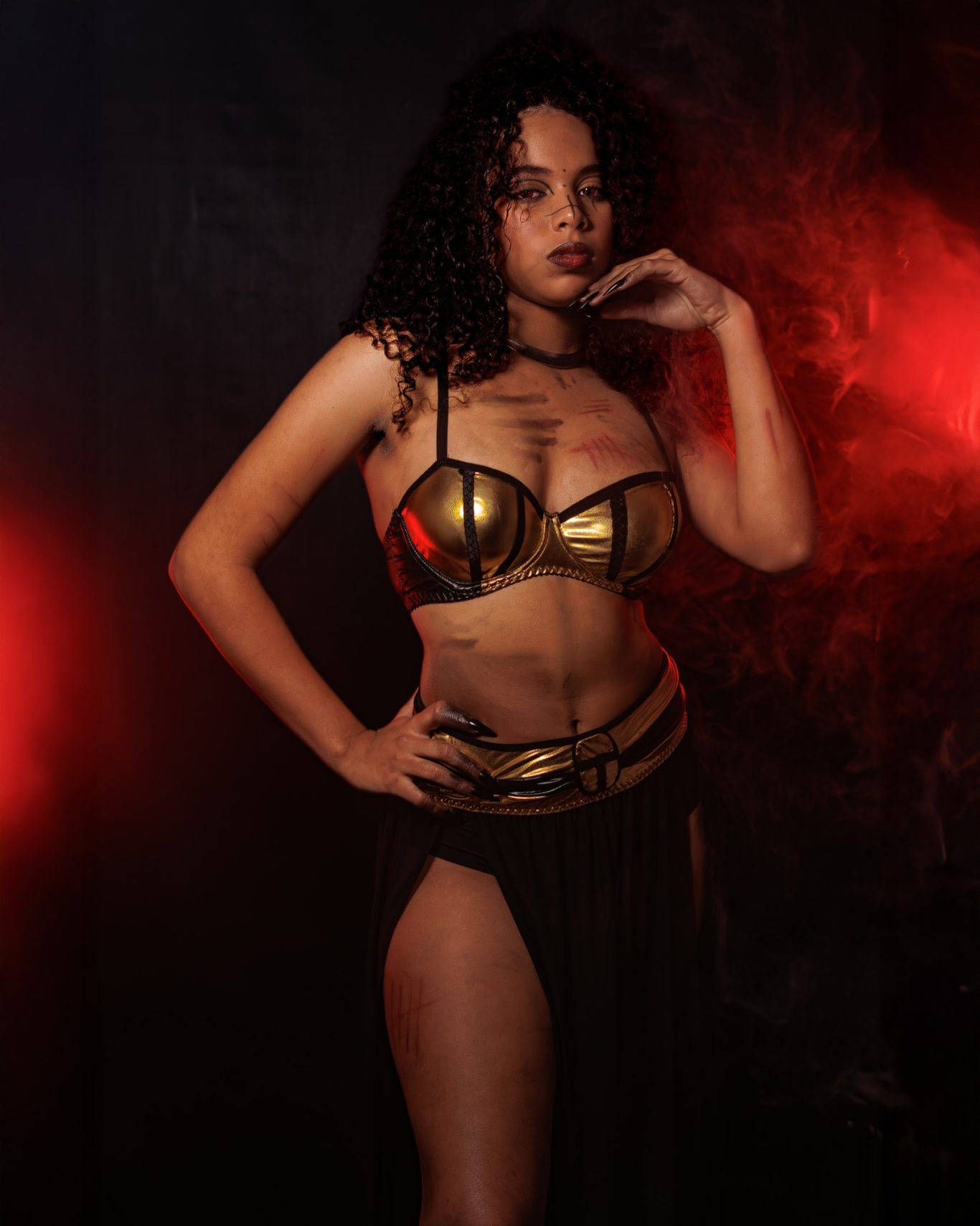 Mujer con brazalete dorado y vestido oscuro, posando con actitud segura.
