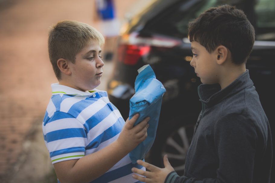 Dos niños interactuando, uno sostiene un objeto azul mientras el otro observa.