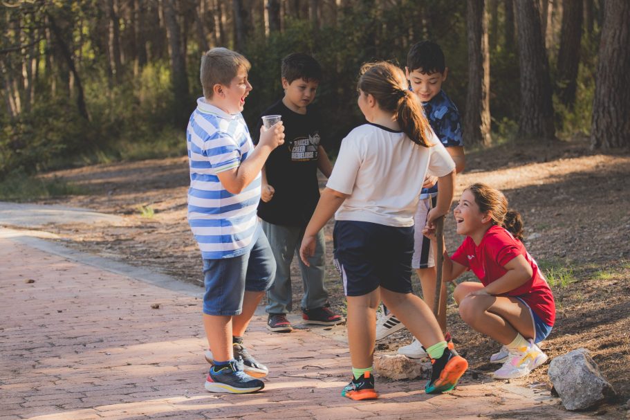 Niños jugando y conversando en un sendero natural. Algunos observan algo en el suelo.