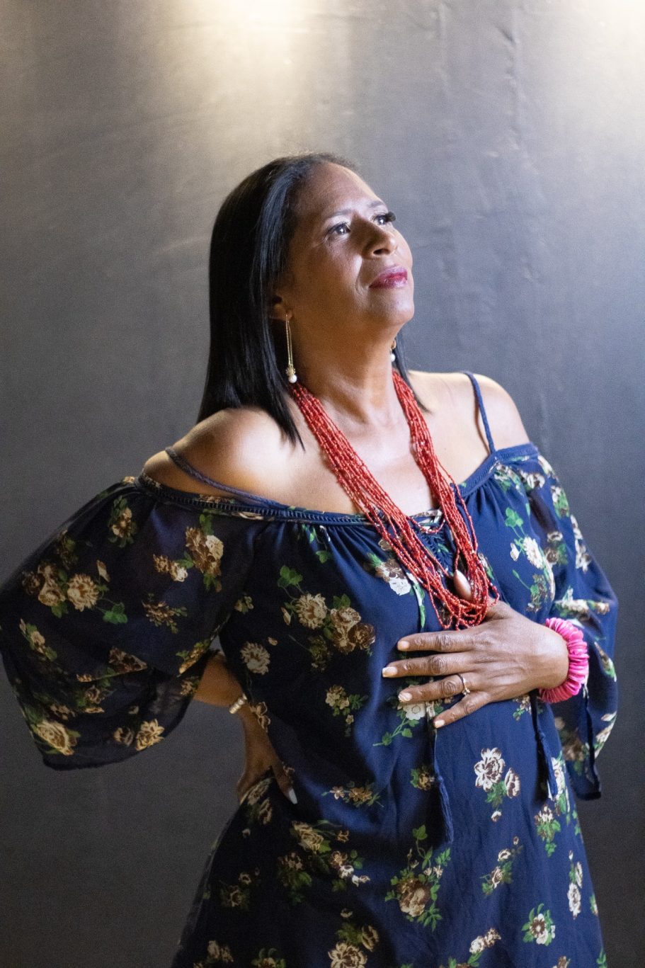 Mujer de cabello largo y suelto, vestida con blusa floral, posando con expresión serena.