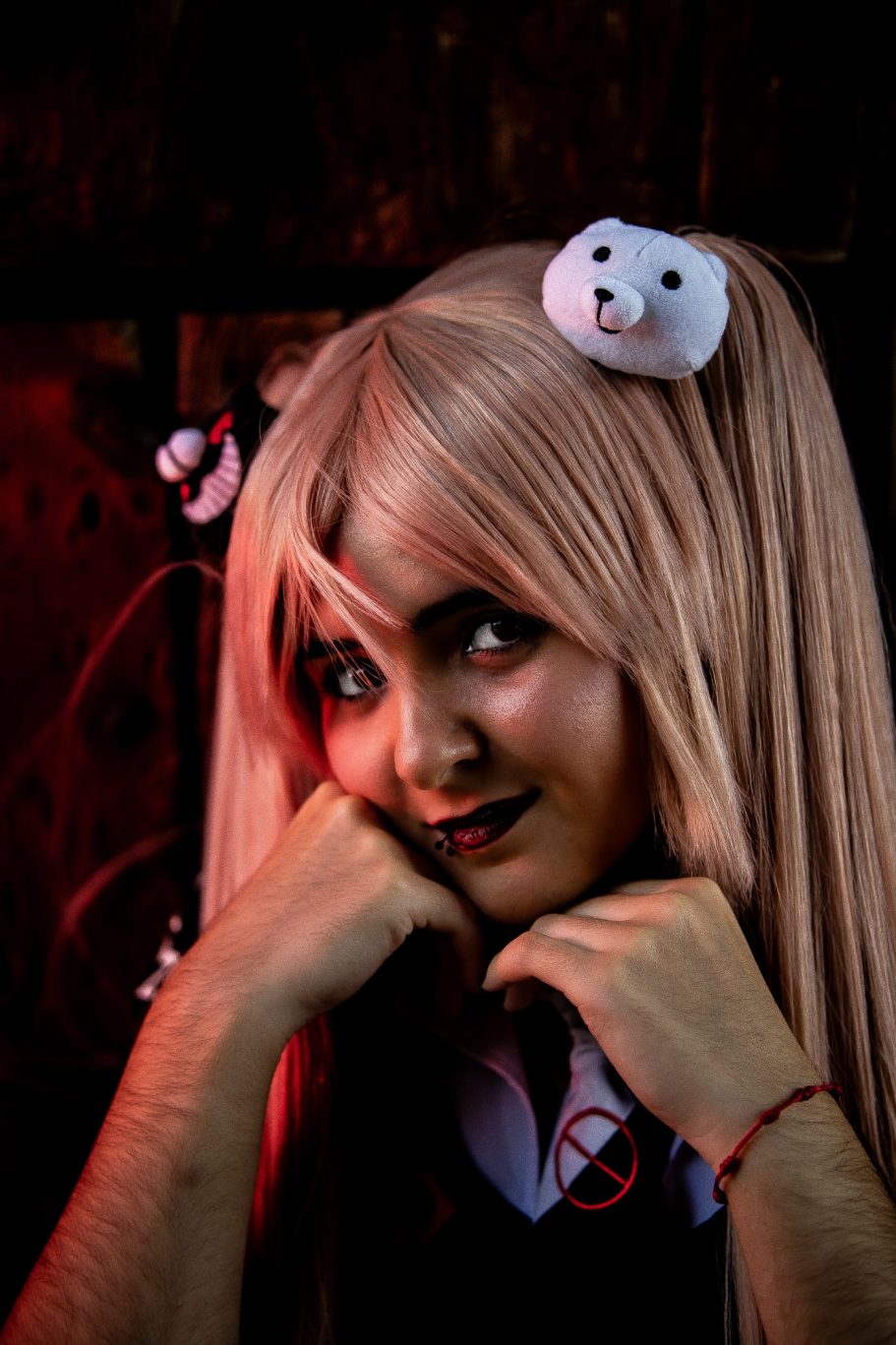 Joven con cabello largo y rubio, usando orejas de peluche, sonriendo con mirada traviesa.